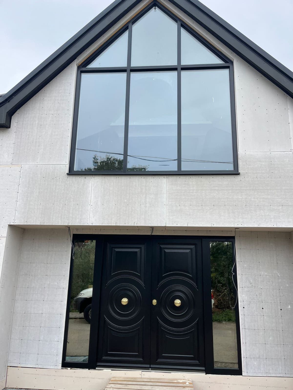 Black ornate double steel doors under gabled porch