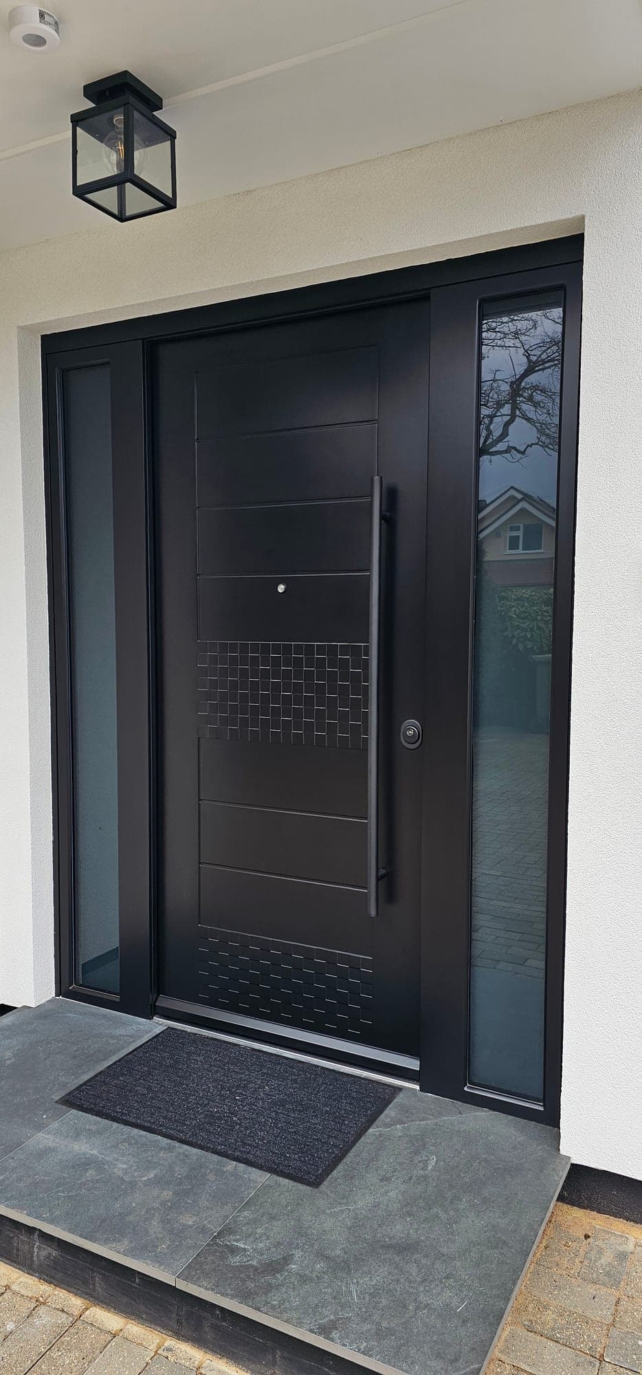 Black panelled steel door with decorative grille