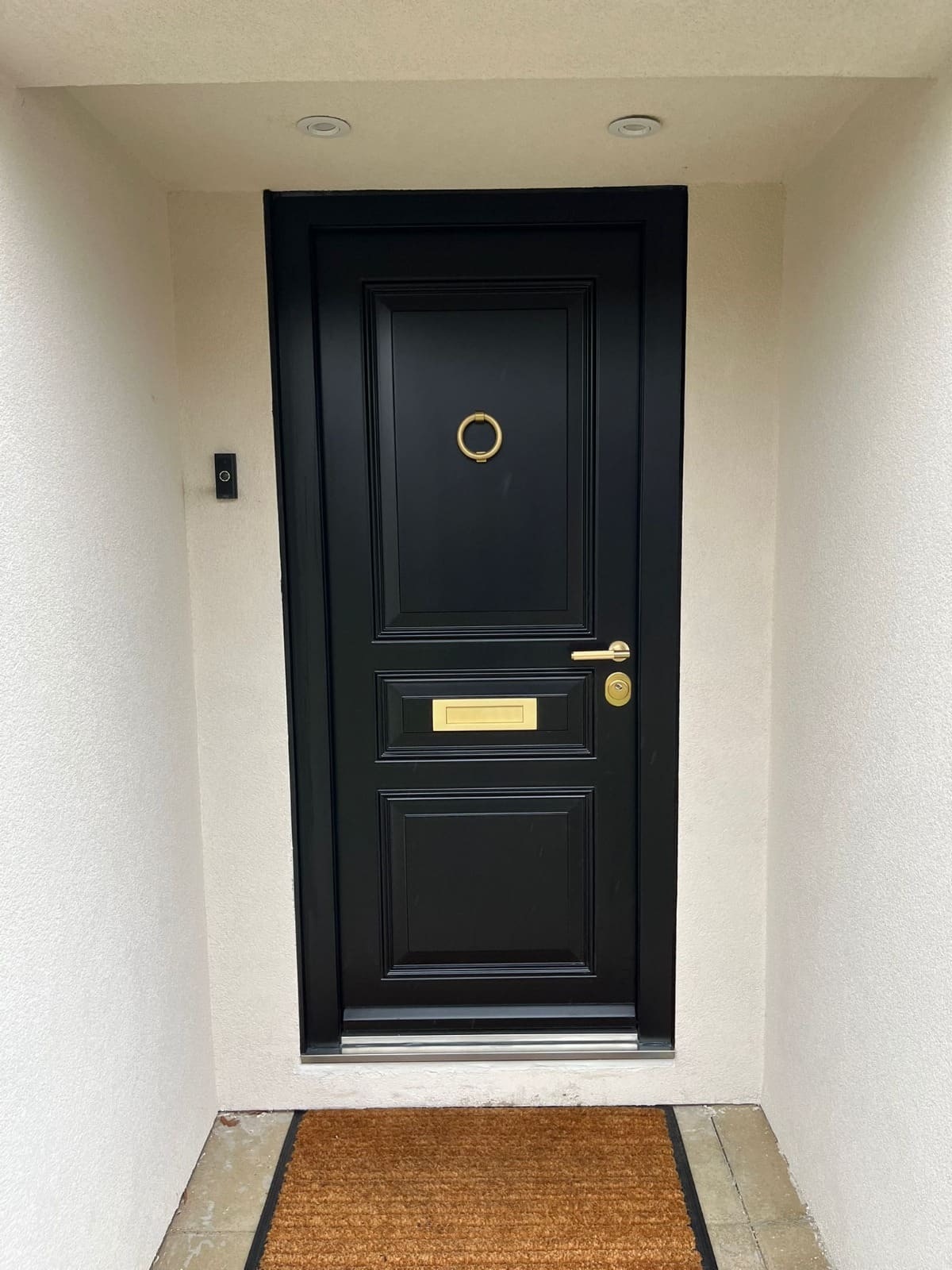 Black steel entrance door with ring knocker in a recessed porch — high-security front door