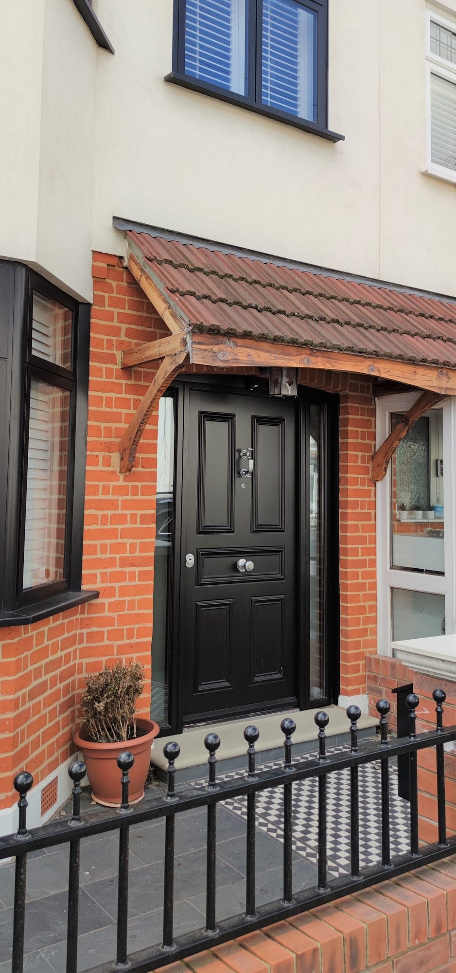 Black traditional 5-panel steel door with doctor knocker and wrought iron railings