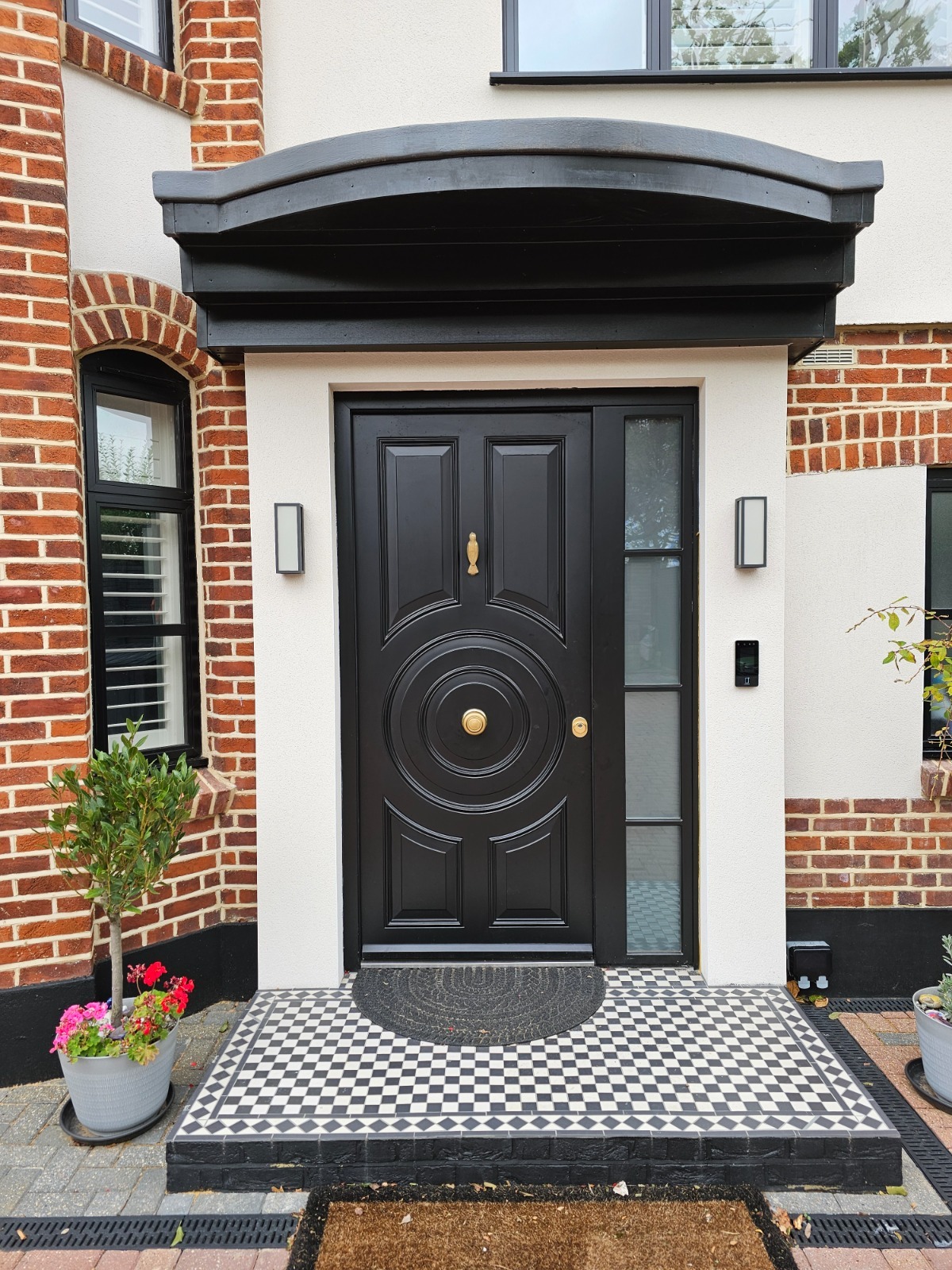Black ornate steel door with checkerboard step and canopy